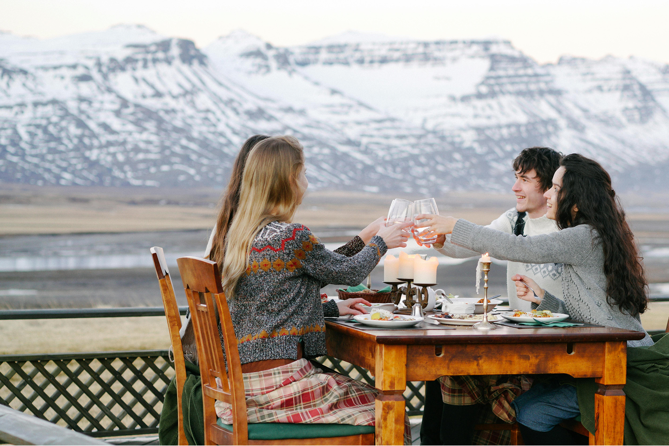 Three people sitting at a table with a scenic view of mountains and water.